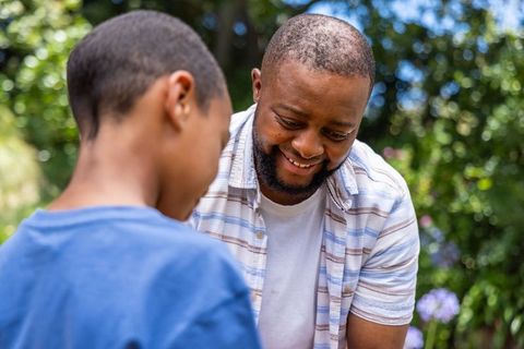 African american father teaching son gardening and laughing in sunlit backyard bonding moment