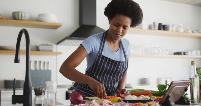 Happy african american woman preparing dinner in kitchen. domestic lifestyle, spending free time at home.
