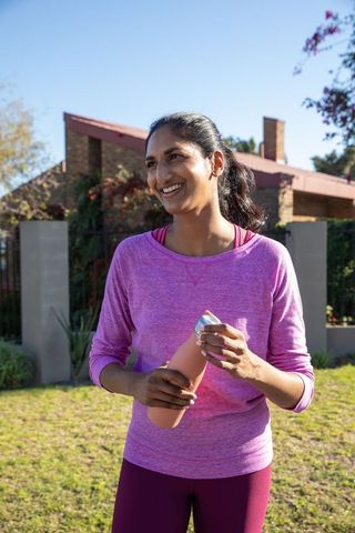 Smiling Woman Holding Reusable Water Bottle Outdoors