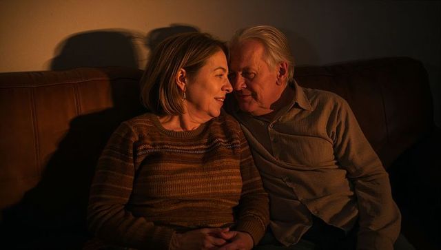 Senior couple sharing intimate moment on leather sofa in warm lamp light