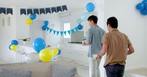 Men Preparing Living Room for Birthday Celebration with Balloons