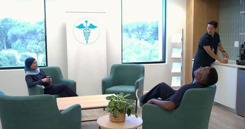 Healthcare team relaxing in bright staff lounge with hijab-wearing clinician and coffee