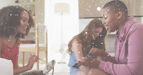 Friends sharing makeup, trying cosmetics and laughing in cozy sunlit living room