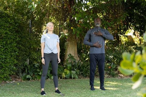 Mature couple practicing mindful breathing in backyard garden for wellness and fitness