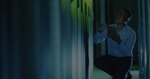 IT Technician Inspecting Servers in Data Center Using Tablet