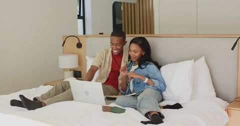 Couple Planning Vacation Together, Relaxing with Laptop in Bedroom