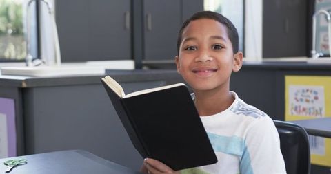 Young african american student reading book in classroom