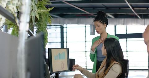 Multicultural team collaborating and reviewing data dashboards in sunlit modern office