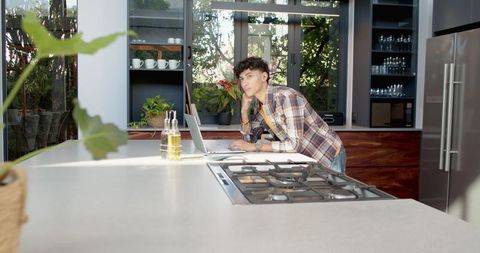 Young Man Using Laptop in Modern Kitchen Environment