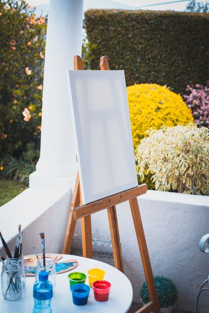 Blank painting canvas sitting on easel on terrace in summer garden. creative hobbies at home at home during quarantine lockdown.