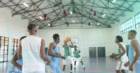 Indoor basketball scrimmage with player protecting ball under hoop, teammates converging