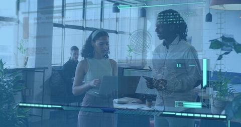 Coworkers collaborating with laptop and tablet in open office using augmented hud