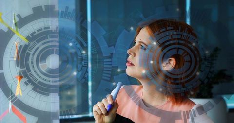 Businesswoman annotating futuristic holographic data interface on office glass panel