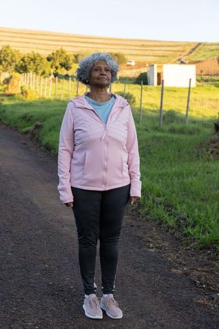 Senior woman embracing pastoral wellness on gravel road