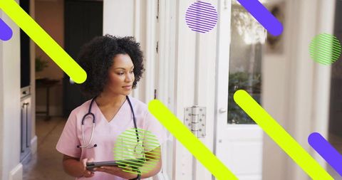 Nurse standing in clinic doorway holding tablet wearing pink scrubs and stethoscope