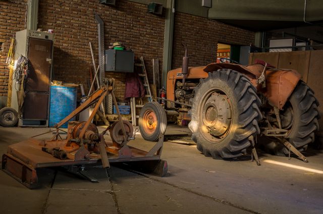 Captured during restoration, this vintage tractor sits in a garage amidst various tools and equipment. Ideal for concepts related to antique machinery, agricultural history, restorations, or farming nostalgia.