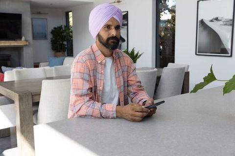 Man in lavender turban using smartphone in contemporary dining area