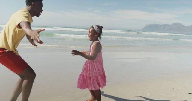 Father and daughter running and playing on a sandy beach with ocean waves in background. Perfect for family vacation themes, summer activities, parent-child bonding, outdoor fun, and carefree moments by the seaside.