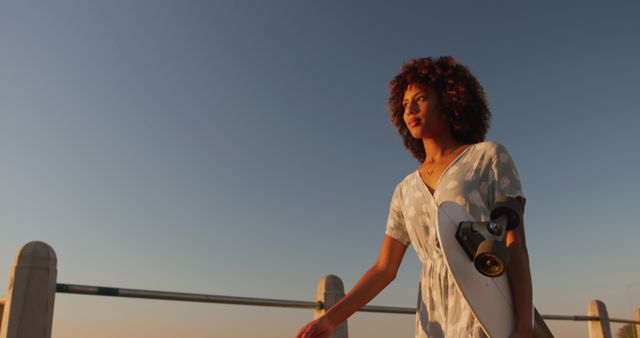 Young Woman With Curly Hair Walking at Sunset Holding Skateboard - Download Free Stock Images Pikwizard.com