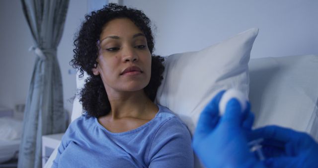 A doctor wearing blue gloves prepares a patient for an injection. Ideal for medical blogs, healthcare websites, patient care articles, and hospital promotional materials.