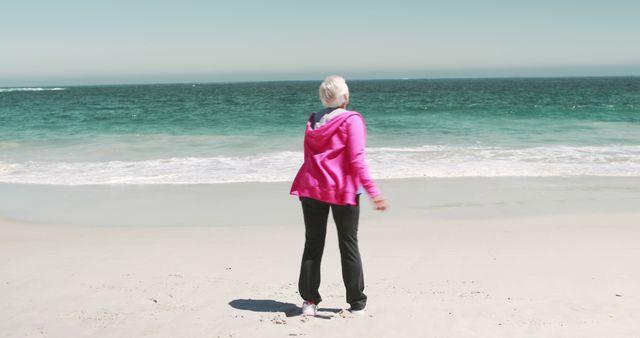 Old retired woman doing some stretching on the beach