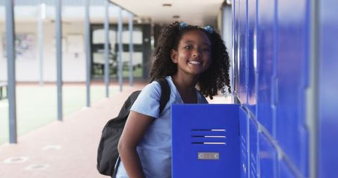 African American Girl Smiling by Blue School Lockers