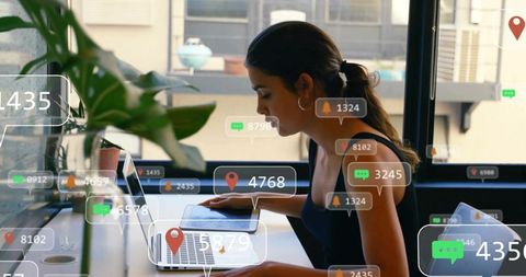 Working woman using laptop with ar notification overlays in modern urban coworking space