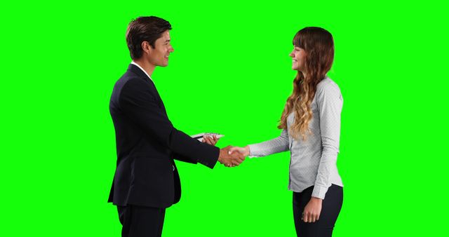 Two business professionals shaking hands in agreement, both dressed in formal attire, on a green screen background. Ideal for use in presentations, promotional materials, or marketing designs focusing on business partnerships, cooperation, or successful negotiations.