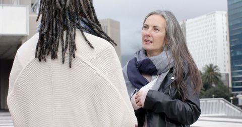 Diverse women chatting on urban rooftop deck wearing scarves and leather jackets