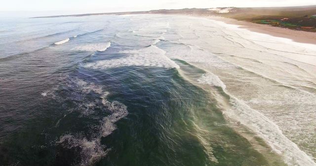 Aerial view of waves reaching a shore at beach on a sunny day 4k