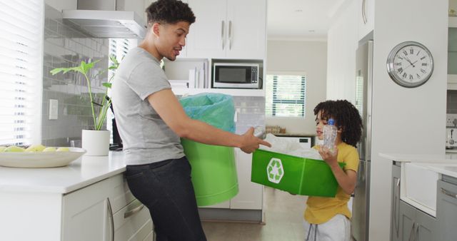 Happy biracial man and his son sorting waste in kitchen. domestic life, spending time at home.