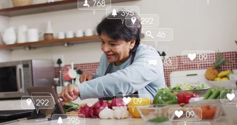 Senior indian woman livestreaming cooking class preparing fresh vegetables on tablet