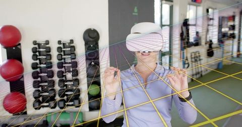 Woman using vr headset for interactive gym workout with virtual grid augmented overlay