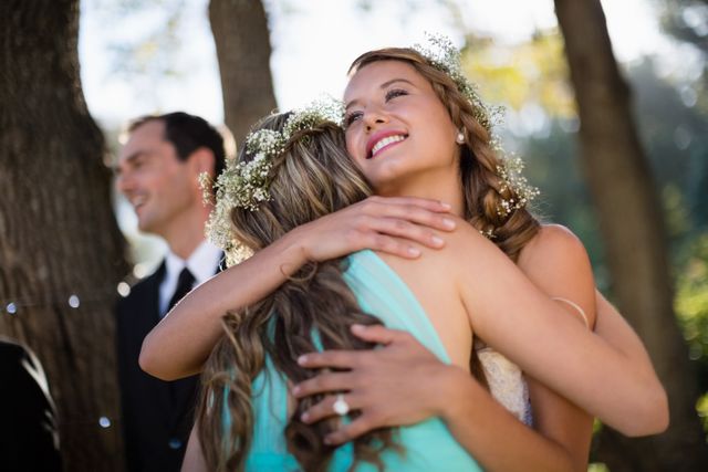 Bride embracing her friend in park during wedding