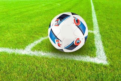 Soccer ball resting in corner on vibrant green grass with crisp white field lines