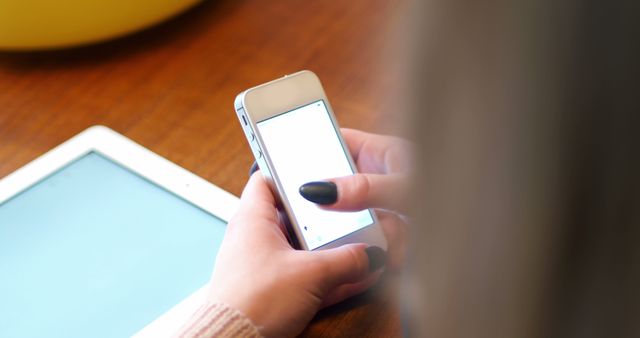 Rear view of woman text messaging on mobile phone at home