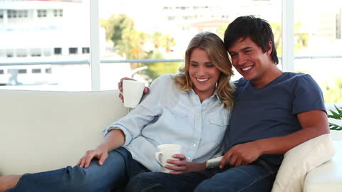 Happy Couple Relaxing on a Sofa Watching TV Together