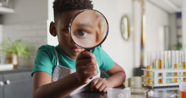Image of african american boy with magnifier doing experiments at home. Childhood, curiosity, education, spending free time at home concept.