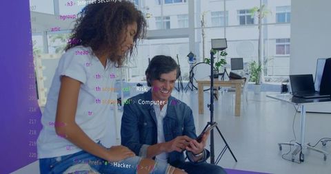 Creative tech team collaborating in modern open-plan studio tapping phone with code overlay