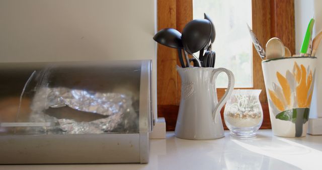 Kitchen utensils sit in a ceramic holder by a window, with copy space - Download Free Stock Photos Pikwizard.com