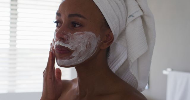 Woman Applying Face Mask with Towel Wrapped Around Hair - Download Free Stock Images Pikwizard.com