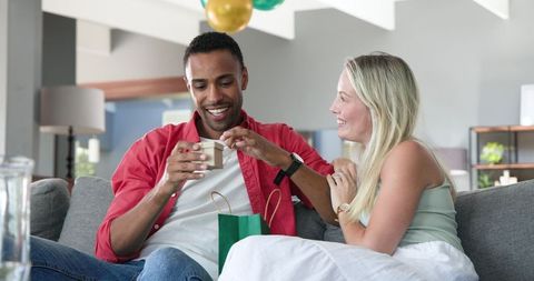 Joyful couple celebrating birthday with gift unboxing