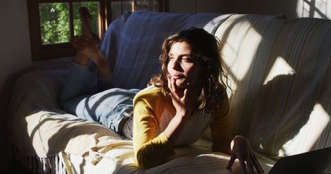 Woman Relaxing on Couch with Sunlit Ambiance