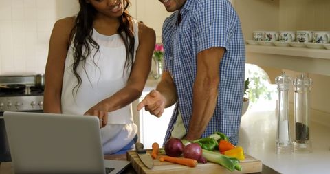 Young Couple Cooking Together with Laptop in Modern Kitchen