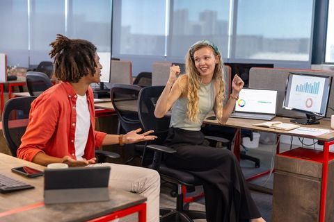 Diverse Coworkers Celebrating Success Analyzing Chart Data in Modern Office