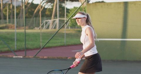 Female Tennis Player Preparing Forehand on Outdoor Court Wearing Visor and Black Skirt