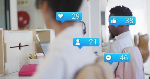 Office worker typing on laptop with social media notification badges in open-plan workspace