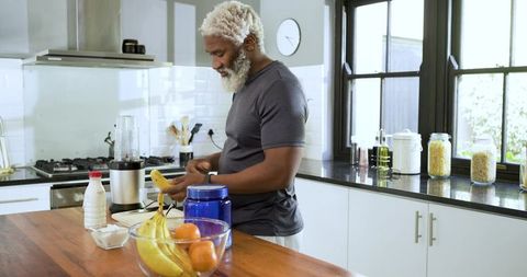 Senior man preparing smoothie in home kitchen