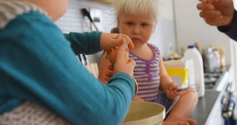 Small Children Helping Father Crack Eggs in Kitchen for Cooking