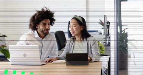 Collaborating team members using laptop and tablet at modern open-plan office desk
